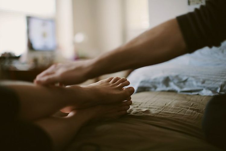 Девушка обнимает ногу. Руки в постели. Мужчина обнимает ноги женщины. Поглаживание женских ног. Переплетение ног в постели.